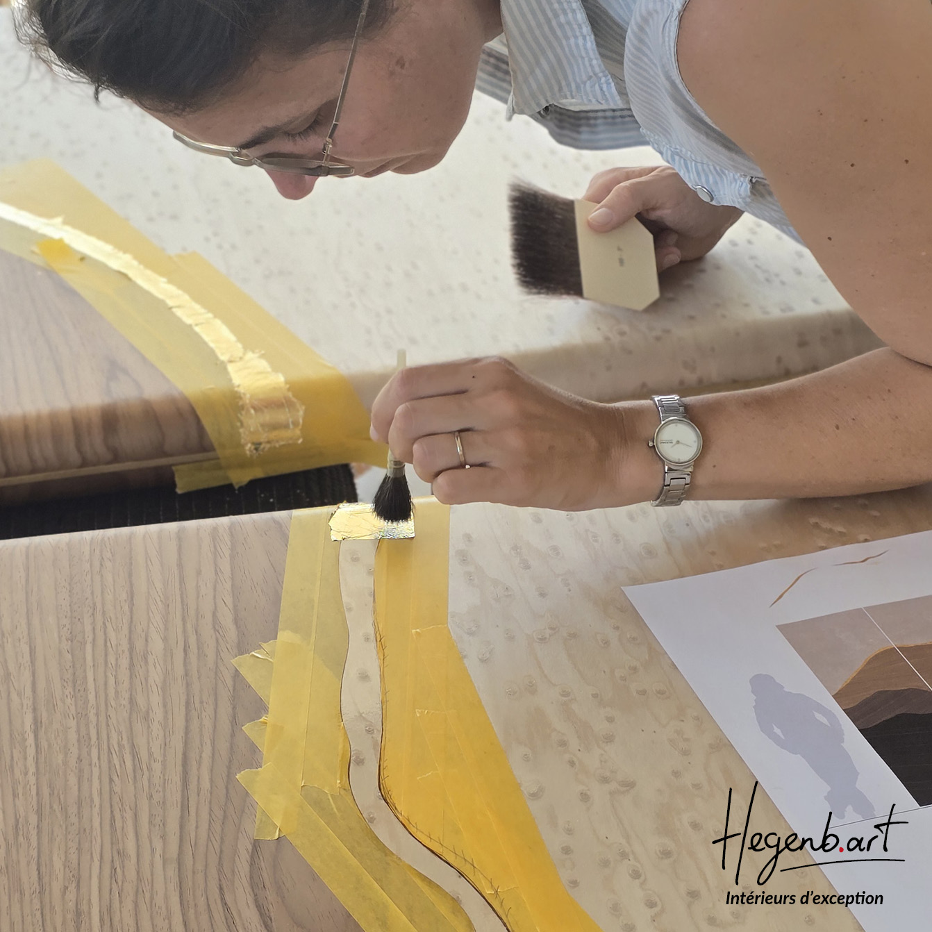 Dorure à la feuille d'or en cours d'application sur porte pivot PAYSAGE - Collection Signature Hegenbart